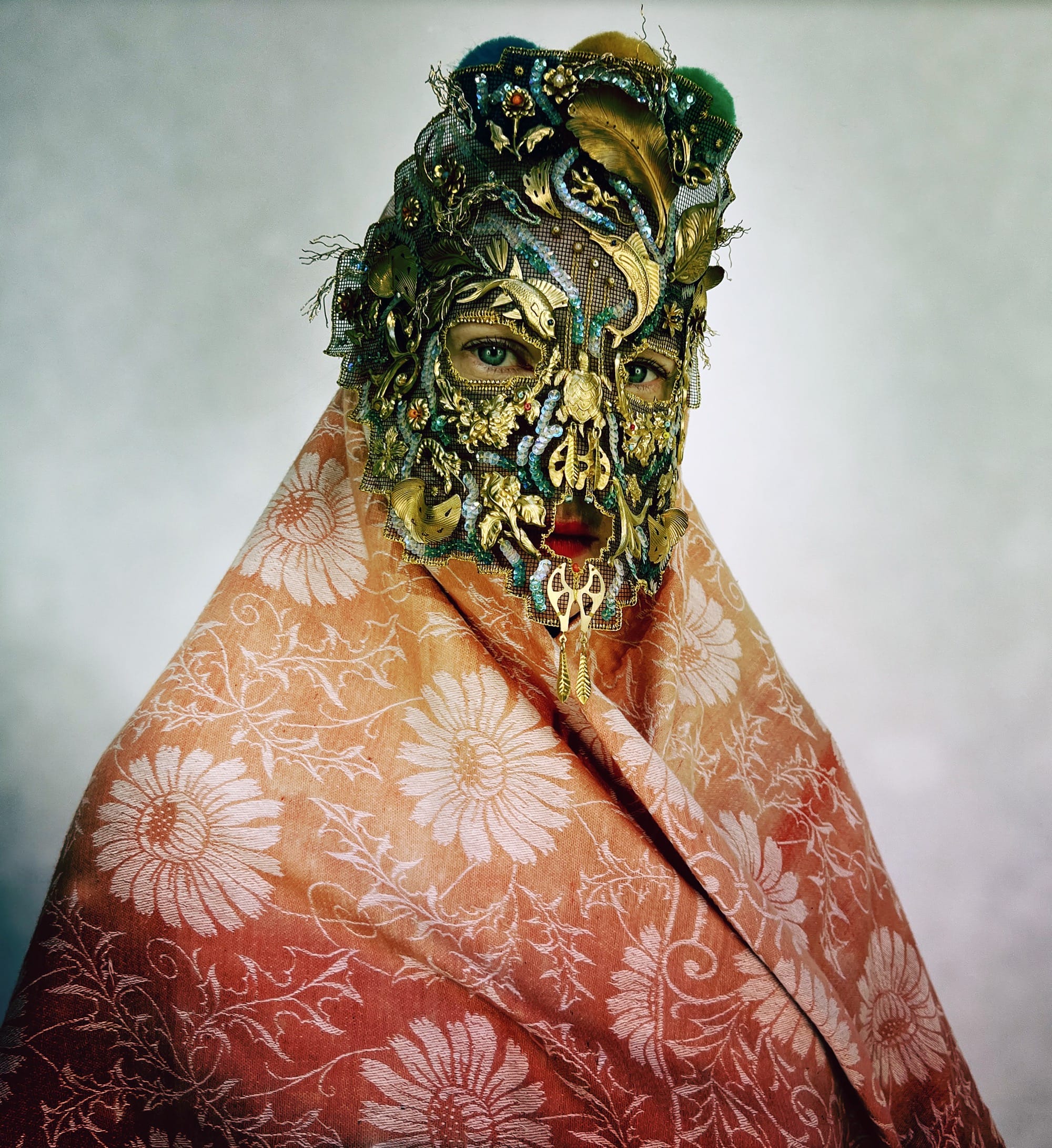 an ornate mask by Magnhild Kennedy with swirling blue and yellow and a patterned peach textile covering the body