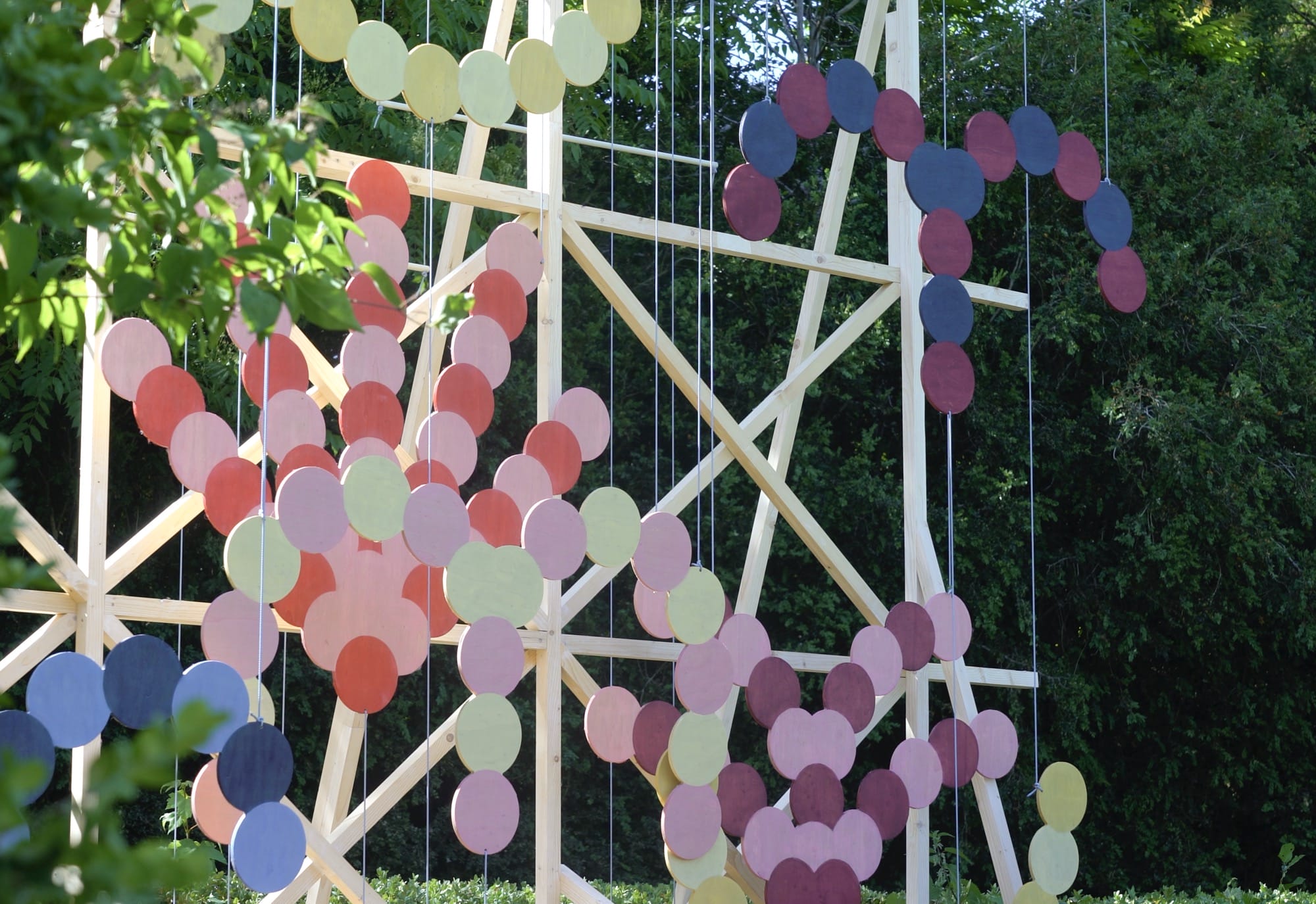 A close-up image of a kinetic installation by Pinaffo & Pluvinage of colorful discs suspended on a slender scaffold.