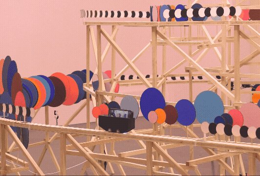 A gif of a kinetic installation by Pinaffo & Pluvinage of colorful discs on a track framework.