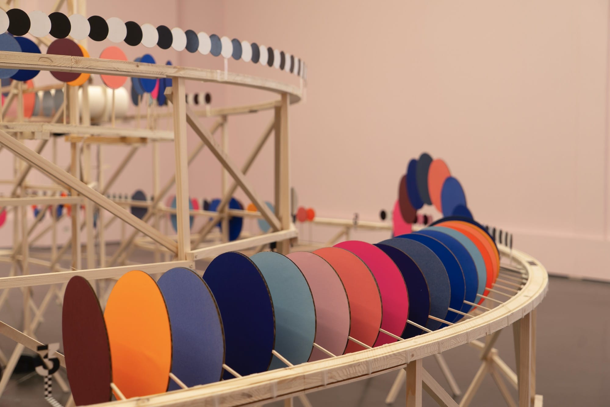 A close-up image of a kinetic installation by Pinaffo & Pluvinage of colorful discs on a track framework.